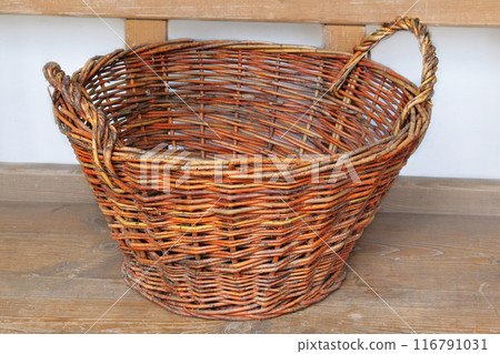 Retro straw basket on a wooden bench. Vintage container in cottage kitchen. Country life. 116791031