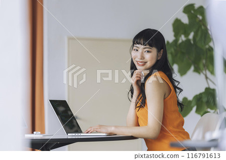Young woman working on laptop, looking at camera, portrait 116791613