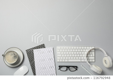 A cup of coffee with headphones and a keyboard on a light background 116792948