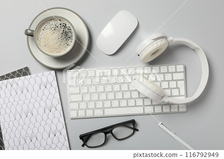 A cup of coffee with headphones and a keyboard on a light background A cup of coffee with headphones and a keyboard on a light background 116792949