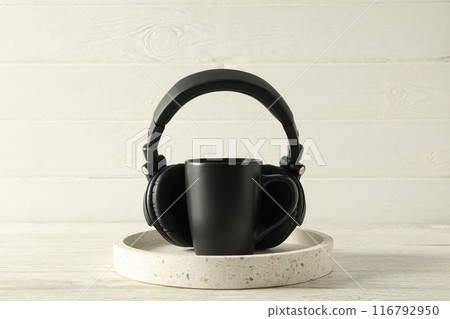 Black cup with black headphones on a light background Black cup with black headphones on a light background 116792950