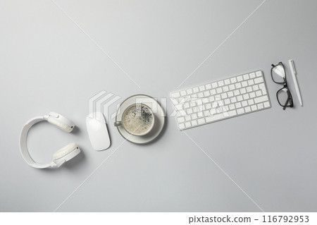 A cup of coffee with headphones and a keyboard on a light background A cup of coffee with headphones and a keyboard on a light background 116792953