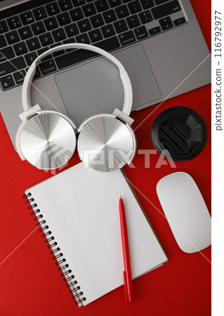 A cup of coffee with headphones and a laptop on a red background 116792977