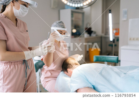 Male patient receiving hair loss treatment injections in scalp by trichologist. Dermatologist in mask performing local anesthesia to back of head in recipient area prior to hair transplant surgery. Male patient receiving hair loss treatment injections in scalp by trichologist. Dermatologist in mask performing local anesthesia to back of head in recipient area prior to hair transplant surgery. 116793854