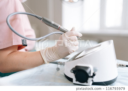 Closeup cropped shot of unrecognizable trichologist specialist in gloves adjusting hair transplant device in clinic. Closeup of female doctor settings apparatus, touching touch screen with finger. Closeup cropped shot of unrecognizable trichologist specialist in gloves adjusting hair transplant device in clinic. Closeup of female doctor settings apparatus, touching touch screen with finger. 116793979