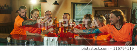 Banner. Group of people happily, joyfully clinking glasses with beer at bar, in moment of celebration win of favorite soccer team. Banner. Group of people happily, joyfully clinking glasses with beer at bar, in moment of celebration win of favorite soccer team. 116794119