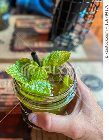 Mojito cocktail in a glass with mint leaves on a wooden bar table  116794176