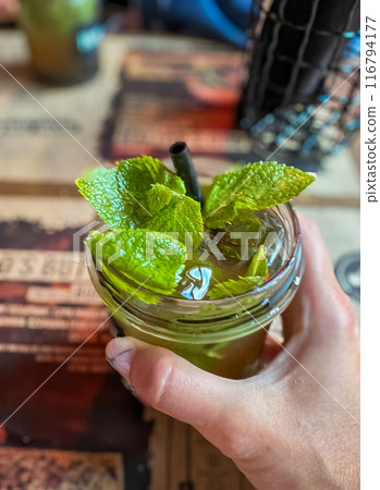 Mojito cocktail in a glass with mint leaves on a wooden bar table  116794177