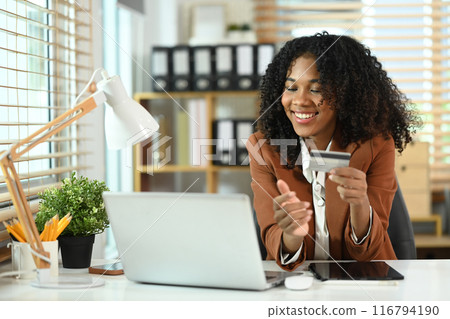 Happy African American businesswoman holding credit card and using laptop for make transactions online 116794190
