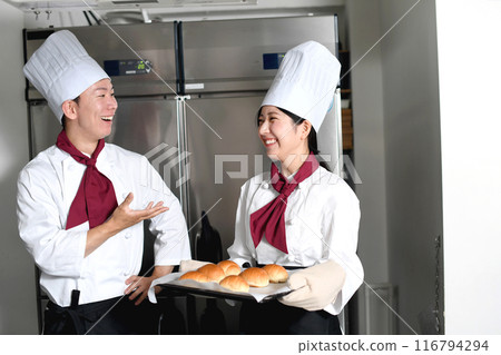 一位男女麵包師傅在麵包店的廚房裡交談 116794294