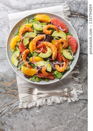 Fresh Cajun shrimp salad with oranges, avocado, grapefruit and leafy greens close-up in a plate. Vertical top view Fresh Cajun shrimp salad with oranges, avocado, grapefruit and leafy greens close-up in a plate. Vertical top view 116794864