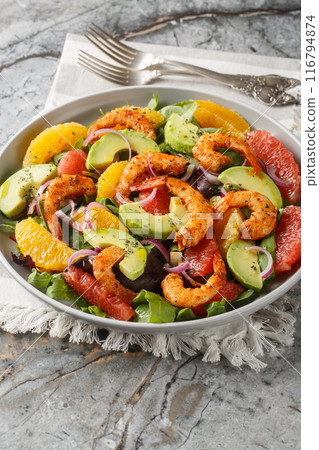 Citrus Cajun Shrimp Salad loaded with greens, shrimp, citrus fruits, and avocado closeup on the plate. Vertical 116794874