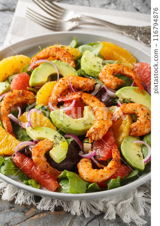 Fresh Cajun shrimp salad with oranges, avocado, grapefruit and leafy greens close-up in a plate. Vertical 116794876