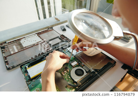 Repairman Screwing The Board Of Laptop Under Magnifier Repairman Screwing The Board Of Laptop Under Magnifier 116794879