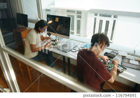 Colleagues Repairing Gadgets In Workshop 116794891