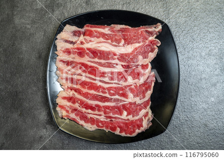 A slab of meat is on a black plate 116795060