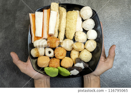 A person is holding a tray of assorted food items 116795065