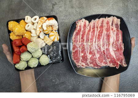 A person is holding two plates of food, one with a variety of vegetables 116795069