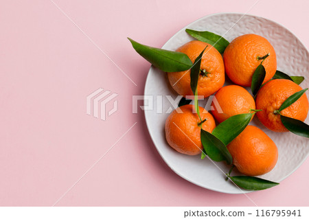 Fresh cutted clementines and whole mandarin over round plate on colored background. Food and drink ingredients preparing. healthy eating theme top view vith copy space Fresh cutted clementines and whole mandarin over round plate on colored background. Food and drink ingredients preparing. healthy eating theme top view vith copy space 116795941