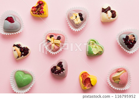 chocolate sweets in the form of a heart with fruits and nuts on a colored background. top view with space for text, holiday concept chocolate sweets in the form of a heart with fruits and nuts on a colored background. top view with space for text, holiday concept 116795952