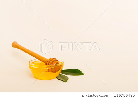 Honey in jar with leaves and honey dipper on colored background top view with copy text Honey in jar with leaves and honey dipper on colored background top view with copy text 116796489