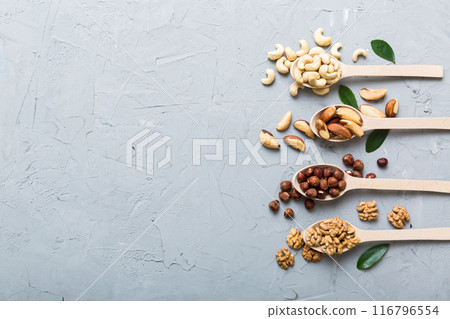 mixed nuts in white wooden spoon. Mix of various nuts on colored background. pistachios, cashews, walnuts, hazelnuts, peanuts and brazil nuts mixed nuts in white wooden spoon. Mix of various nuts on colored background. pistachios, cashews, walnuts, hazelnuts, peanuts and brazil nuts 116796554