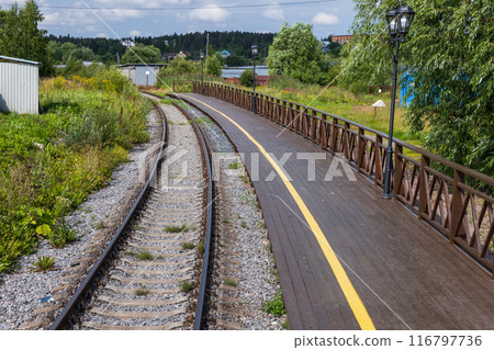 An empty railway track turning left along a station platform An empty railway track turning left along a station platform 116797736