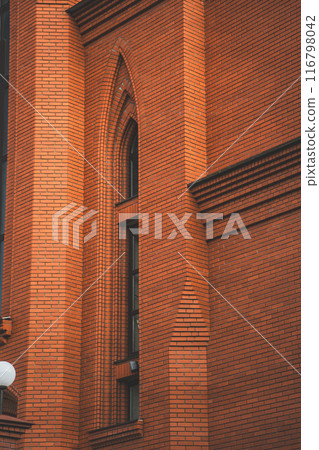 The high, narrow window of the church. The red brick wall of the church 116798042
