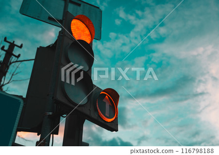 Car traffic light, with a red burning arrow, against the background of the sunset sky 116798188