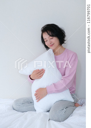 A middle-aged woman holding a pillow to calm her mind and body 116799701