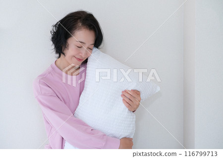 A middle-aged woman holding a pillow to calm her mind and body A middle-aged woman holding a pillow to calm her mind and body 116799713