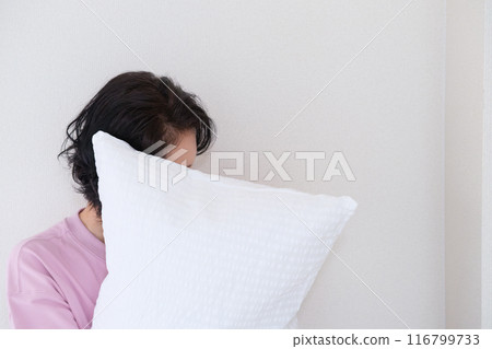 A middle-aged woman holding a pillow to calm her mind and body A middle-aged woman holding a pillow to calm her mind and body 116799733