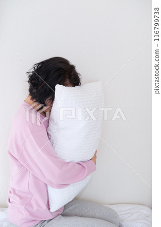 A middle-aged woman holding a pillow to calm her mind and body 116799738