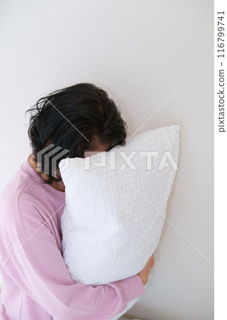 A middle-aged woman holding a pillow to calm her mind and body 116799741