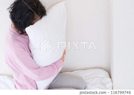 A middle-aged woman holding a pillow to calm her mind and body 116799748
