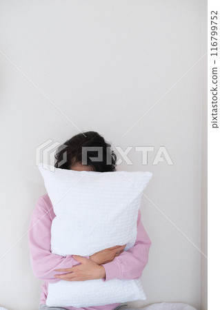 A middle-aged woman holding a pillow to calm her mind and body A middle-aged woman holding a pillow to calm her mind and body 116799752