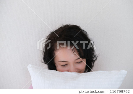 A middle-aged woman holding a pillow to calm her mind and body A middle-aged woman holding a pillow to calm her mind and body 116799762