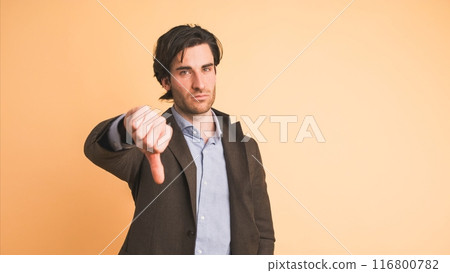 Upset businessman showing thumb down in brown studio Upset businessman showing thumb down in brown studio 116800782