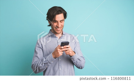 Happy adult man using smartphone in blue studio Happy adult man using smartphone in blue studio 116800811