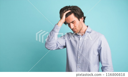Frustrated man suffering from headache in blue studio 116800818
