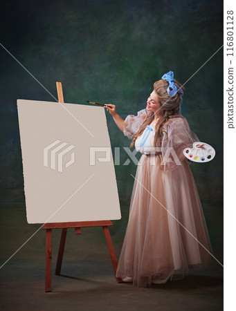 Inspired artist. Happy young woman in period attire standing with palette next to canvas and creating masterpiece, drawing against vintage green background 116801128