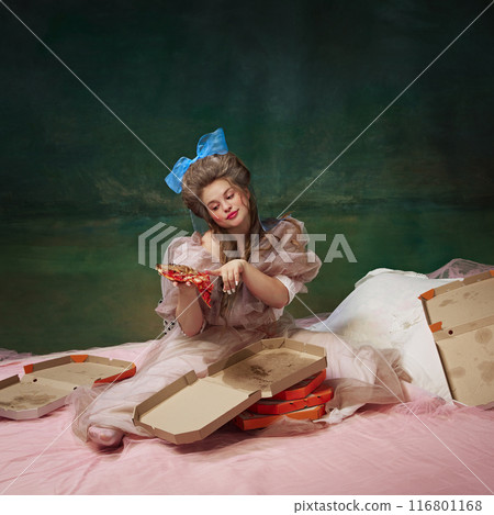 Portrait of beautiful young girl, medieval princess sitting in bed and eating slice of pizza against vintage green background 116801168