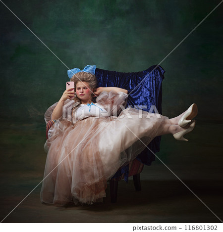 Portrait of young woman, royal person in elegant dress sitting on armchair with bored face and scrolling social media feed against vintage green background 116801302