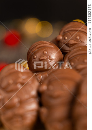 Chocolates in the shape of Christmas figures on the background of a flashing garland Chocolates in the shape of Christmas figures on the background of a flashing garland 116802178