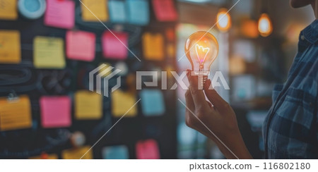 Creative manager holding light bulb with sticky notes in the background Creative manager holding light bulb with sticky notes in the background 116802180