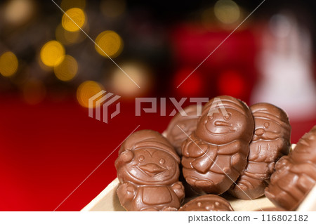 Chocolates in the shape of Christmas figures on the background of a flashing garland 116802182