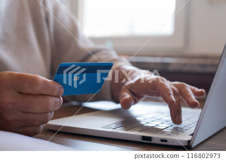 A woman is making an online purchase or payment, utilizing card and a laptop  116802973