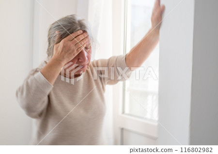 Unhappy mature woman touching head, feeling strong headache, at home alone  116802982