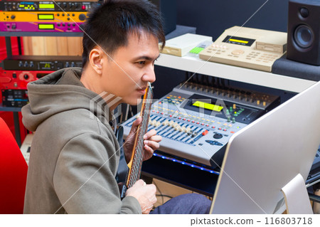 asian male musician playing electric guitar for recording in home studio 116803718