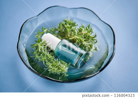 The bottle of serum is blue in water with seaweed. The bottle of serum is blue in water with seaweed. 116804323